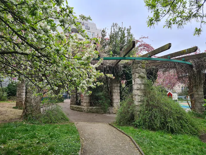 Paysagiste à Paris 13 dans un square avec pergola en pierre et cerisier en fleurs